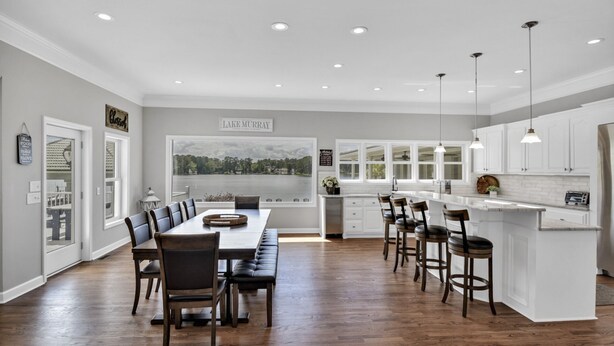 A spacious kitchen with a large island, white cabinetry, and a view of a lake.