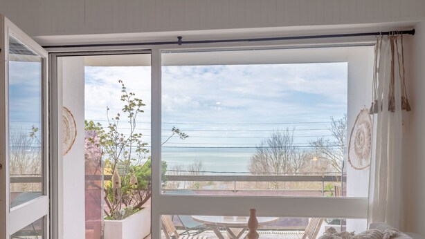 Une pièce dotée d’une grande porte-fenêtre coulissante donnant sur un patio extérieur avec vue sur la mer.