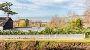 Il s’agit d’une propriété résidentielle offrant une vue sur un plan d’eau, dotée d’un jardin clôturé et d’un bâtiment dont le toit est en pente.
