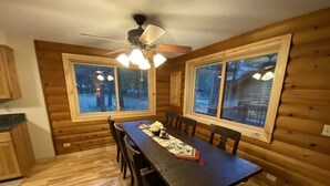A wooden cabin interior with a dining table, chairs, and a ceiling fan. - Sweet Retreat Cozy Cabin (Sisters)