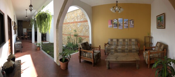 A spacious living area with a sofa set, a dining table, and potted plants.