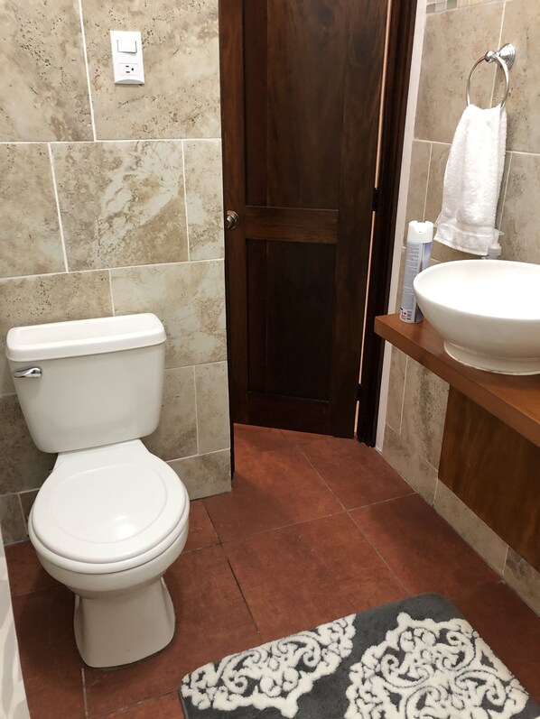 Un baño con inodoro, lavamanos y perchero para toallas.