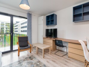 Moderni huoneisto, jossa on parveke, ruokailutila, työtila pöytineen ja tuolineen sekä televisio.