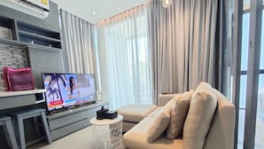 Un salon moderne avec un canapé, un téléviseur et une petite table d’appoint.