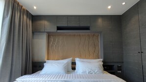 Une chambre d’hôtel moderne avec un grand lit, des murs gris et une tête de lit en bois.