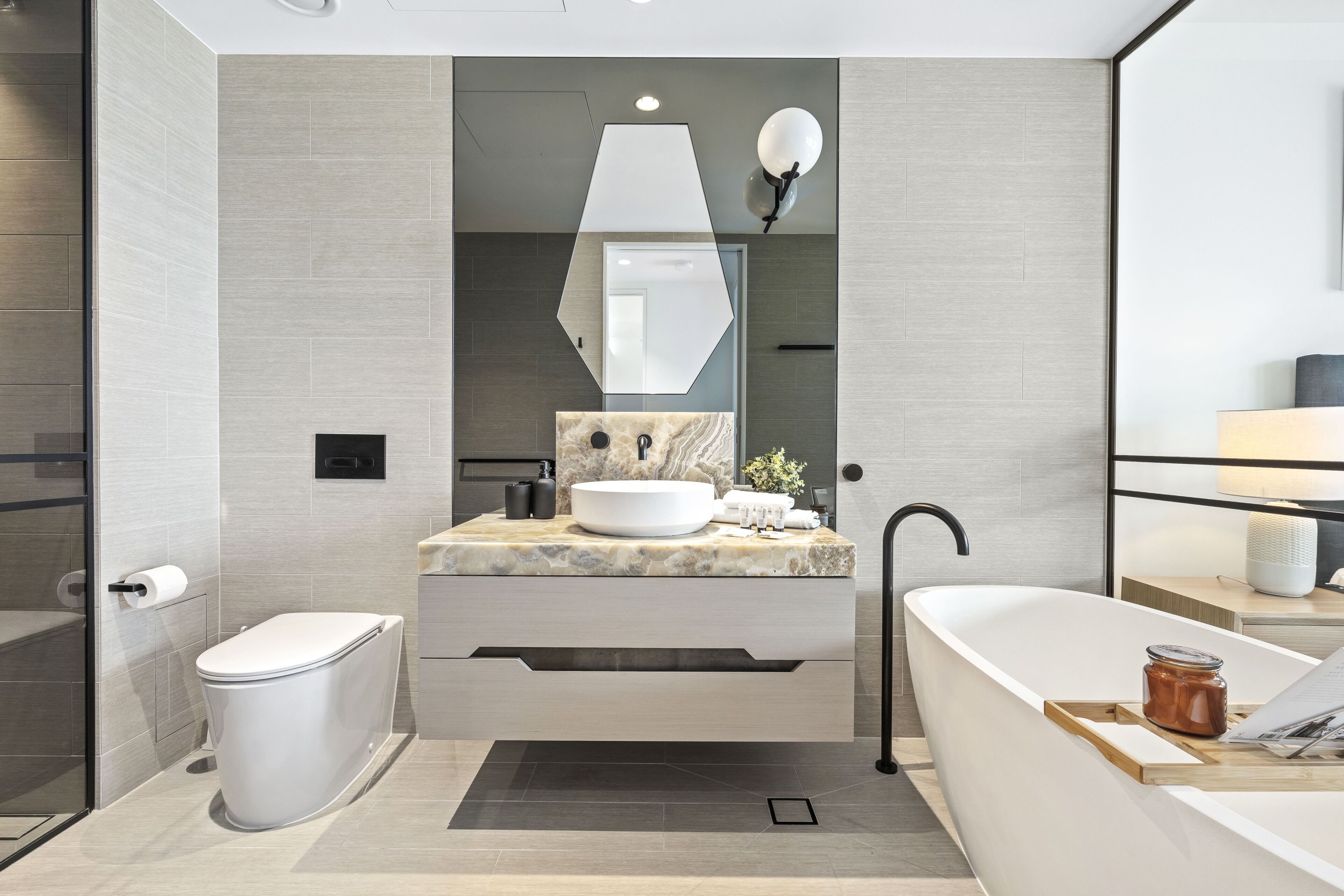 A modern bathroom with a marble sink, a freestanding bathtub, and a glass-enclosed shower.