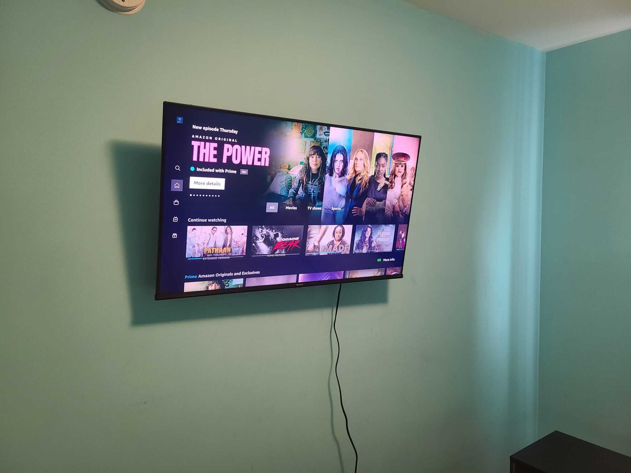 Un téléviseur à écran plat fixé à un mur de couleur turquoise affiche l’interface d’un service de diffusion en continu, et un nouvel épisode de la série « The Power » est disponible.