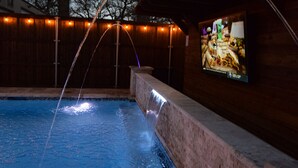 A swimming pool with a water feature and a wall-mounted TV. - Private place to hide away. Endless fun w/pool & game room for multiple families (Fort Worth)