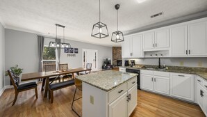 A modern kitchen with white cabinets, granite countertops, and a central island. - Lake Lanier Retreat + Deep Water Dock + Hot Tub (Gainesville)