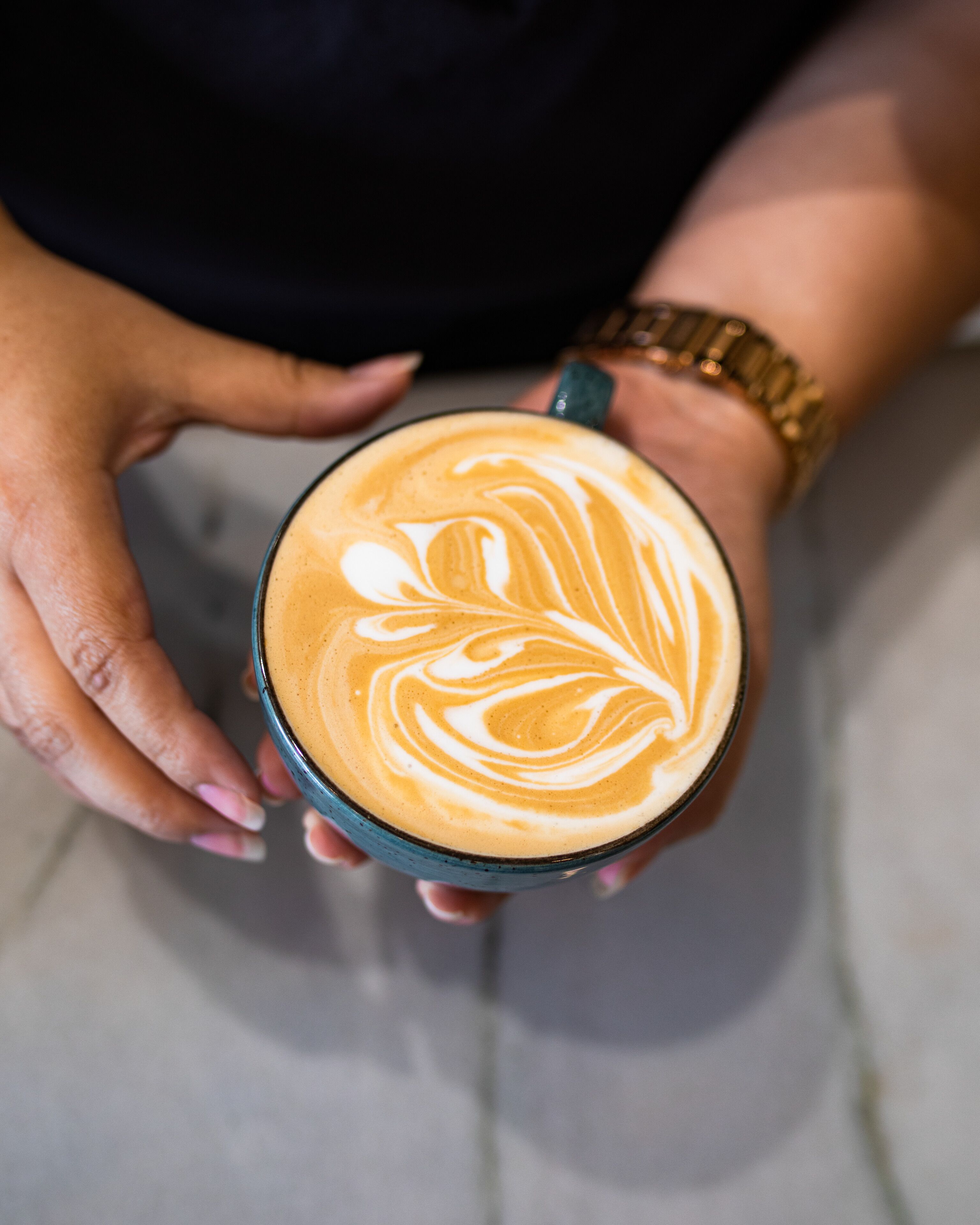 Uma pessoa segurando uma xícara de café com arte de latte.