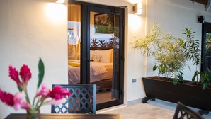 A room with a bed, a sliding glass door, a potted plant, and a table with flowers. - The West House Boutique Hotel (San Ignacio)