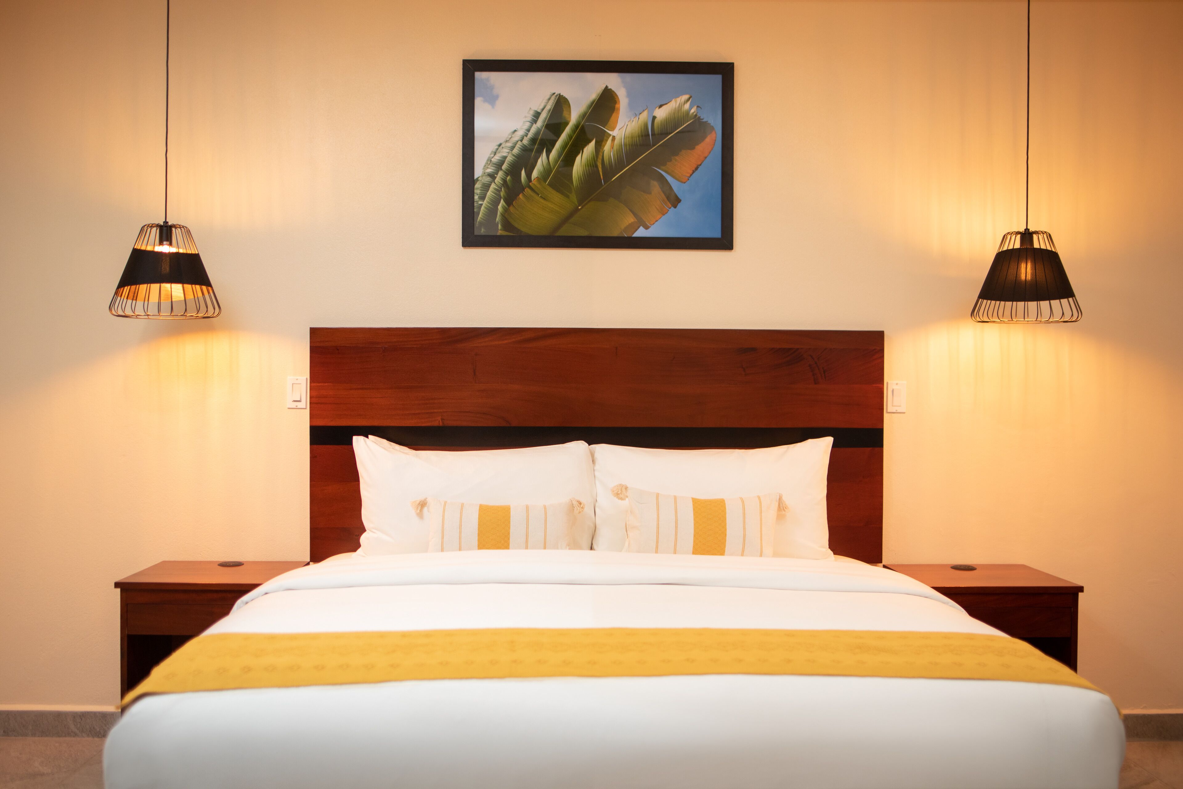 Ein Hotelzimmer mit einem großen Bett, zwei Nachttischen und zwei Hängeleuchten.