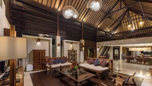 A spacious interior with a high ceiling, wooden furniture, and a central coffee table. - Luxury tropical 5-bedroom villa, five minutes to the beach - Canggu (Bali)