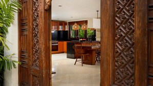 A spacious kitchen with modern appliances, a dining area with wooden furniture, and a decorative wooden door. - Luxury tropical 5-bedroom villa, five minutes to the beach - Canggu (Bali)