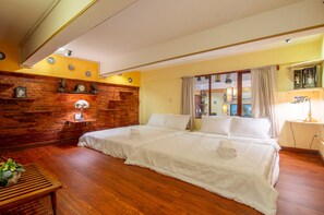 Habitación de hotel con dos camas, piso de madera, una pared de acento de ladrillo y vistas de la ciudad a través de amplias ventanas.