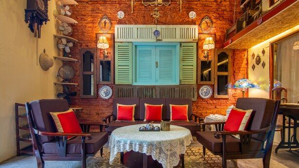 A cozy room with a brick wall, a wooden bench with red cushions, and a small table with a lace tablecloth.