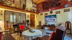 A cozy living room with a high ceiling, wooden furniture, and a television displaying 'Work & Jazz'.