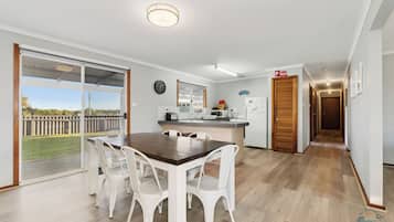 A modern kitchen with a dining area, large windows, and a view of the outdoors.