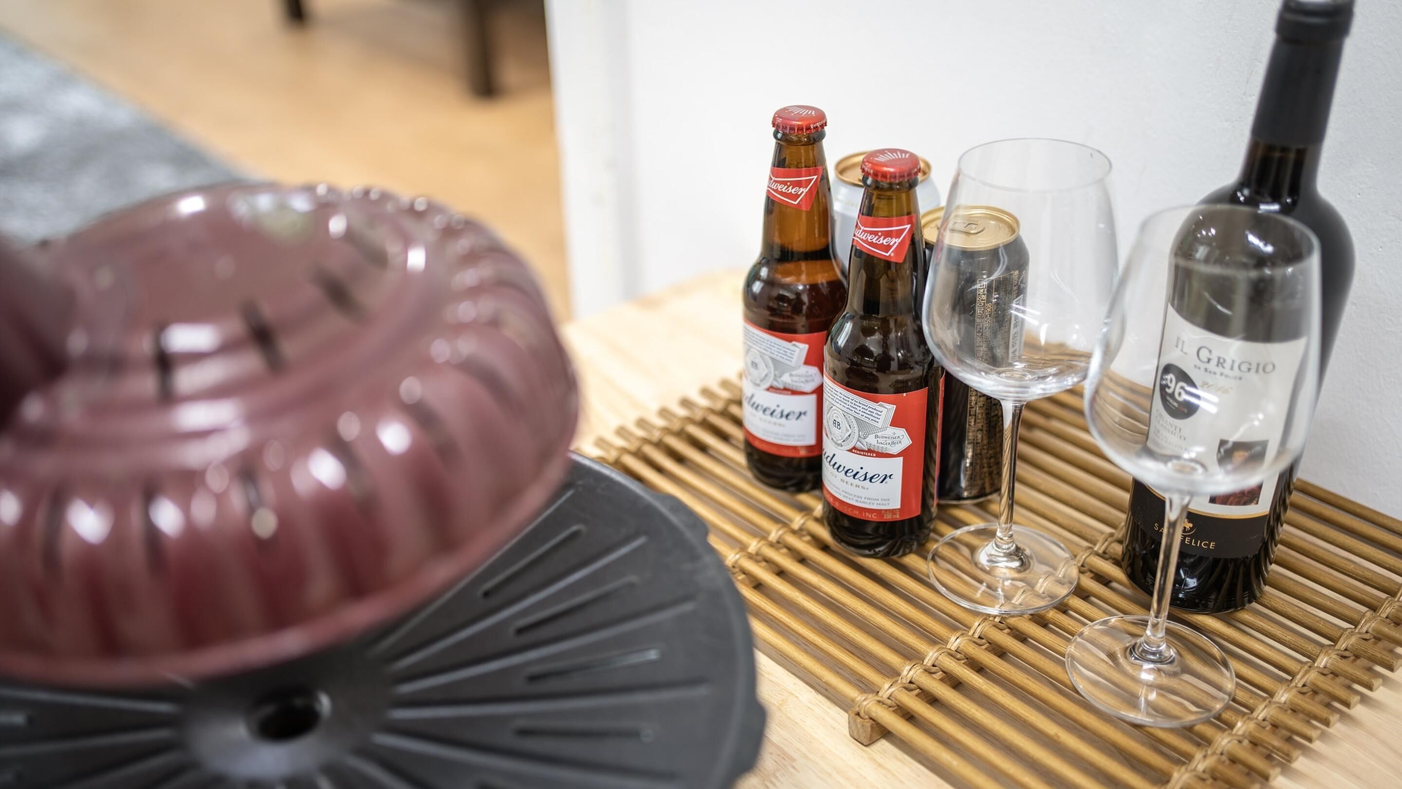 A dining table with a decorative bowl, several bottles of beer, and wine glasses.
