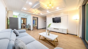 Ein modernes Wohnzimmer mit einer großen Couch, einem Couchtisch und einem an der Wand befestigten Fernseher.