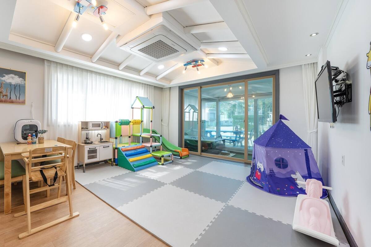 Een kinderspeelruimte met een speelhuis, een glijbaan en een keukengebied.