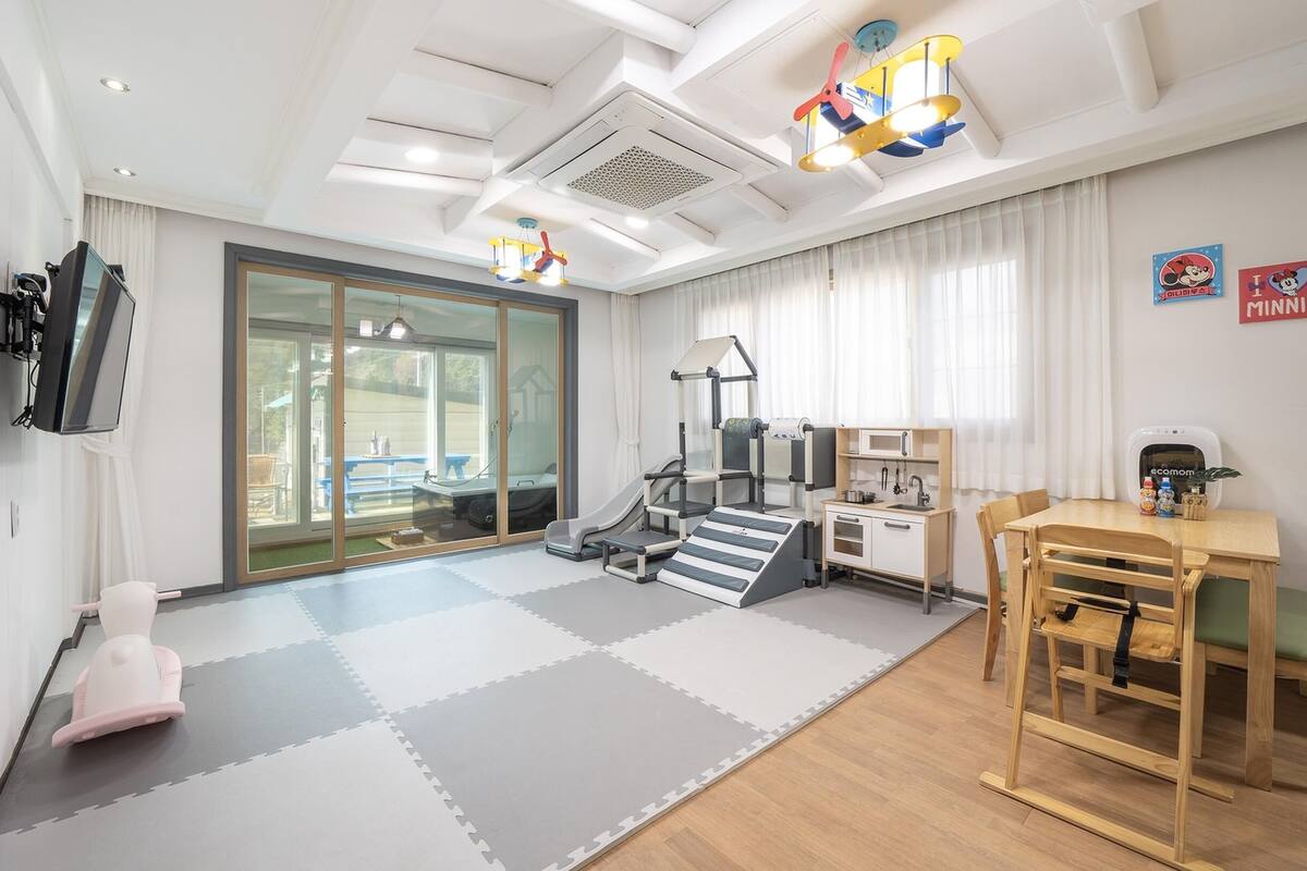 Een kindvriendelijke kamer met een speelhoek, fitnessapparatuur en een kitchenette.