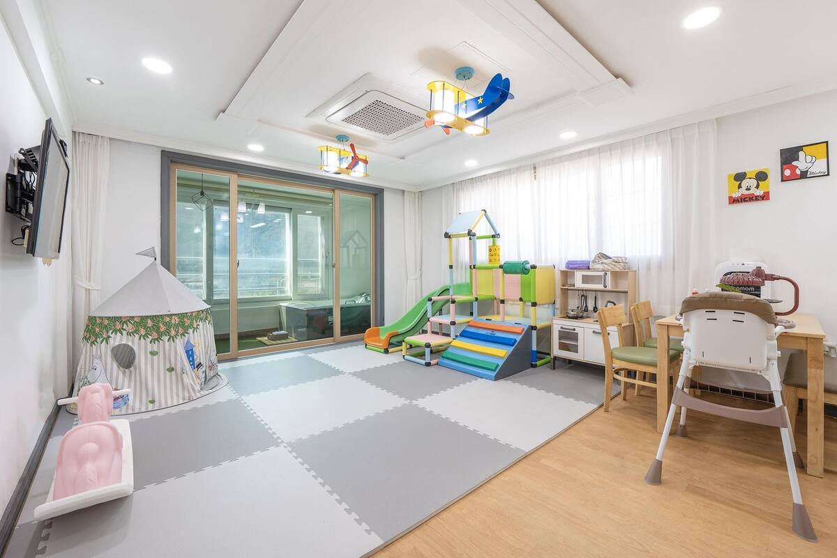 Een kindvriendelijke kamer met een speelruimte, een glijbaan en een huisje.