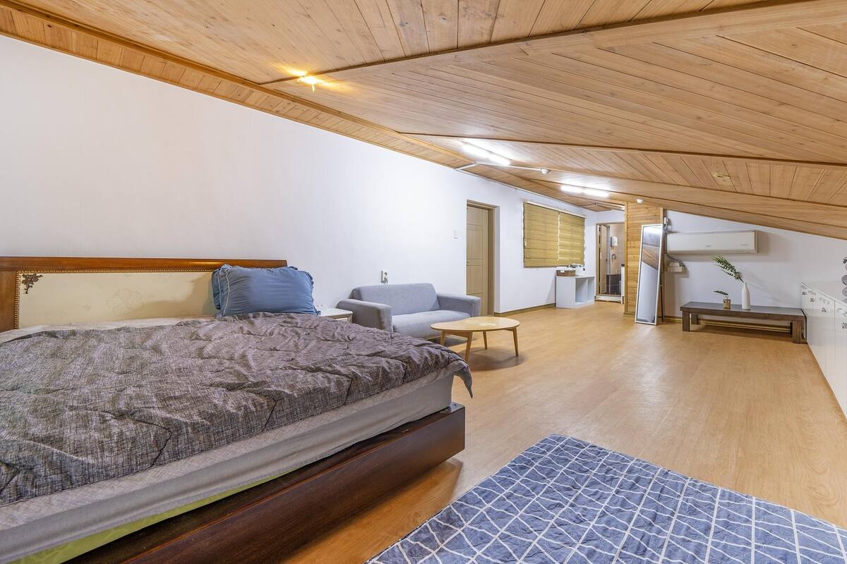 Een slaapkamer met een bed, een slaapbank, een klein tafeltje en een kledingkast.