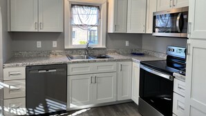 A modern kitchen with white cabinets, a built-in dishwasher, a microwave, and a stove. - Charming 3-bedroom house in delightful Advance with AC, WiFi (Advance)