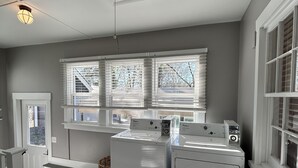 A laundry room with two stacked front-loading washers and dryers, a basket, and a door leading outside. - Charming 3-bedroom house in delightful Advance with AC, WiFi (Advance)