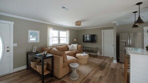 A spacious living room with a sofa set, a coffee table, and a television. - New! Coastal Ranch with Pool and Sauna! (Wilmington)