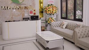 Un espace d’accueil avec un mur en marbre, un comptoir de réception, un canapé, une table basse et une fenêtre donnant sur des rochers et de la verdure.
