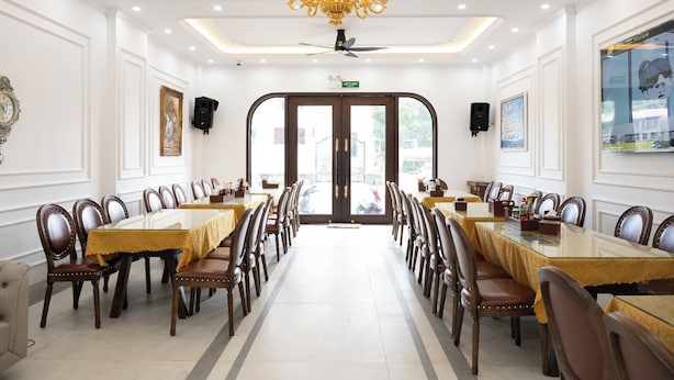 Une salle à manger élégante, avec une longue table, des chaises, un lustre et un ventilateur de plafond.