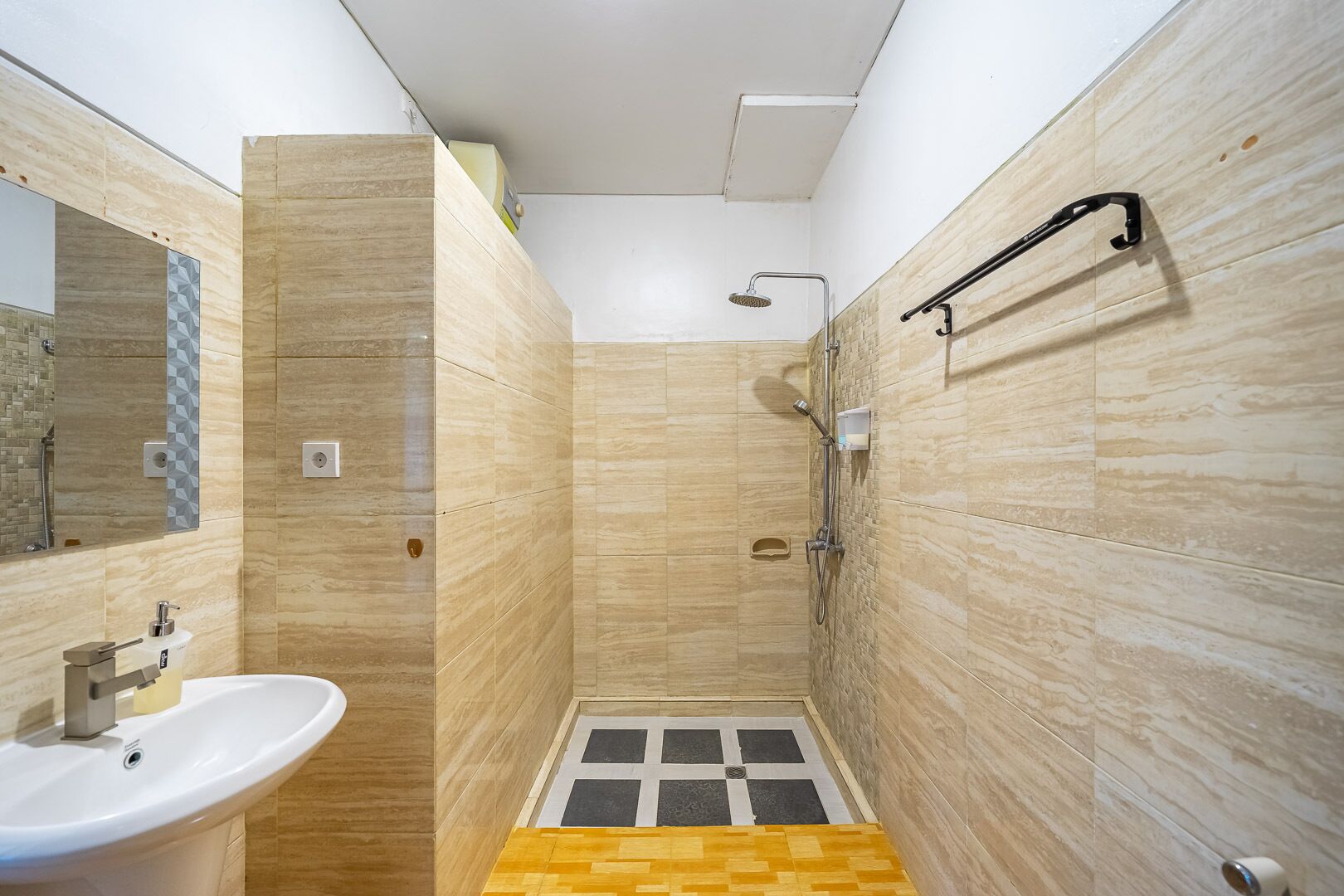 Ein kleines Badezimmer mit Waschbecken, Spiegel, Dusche und Handtuchhalter.