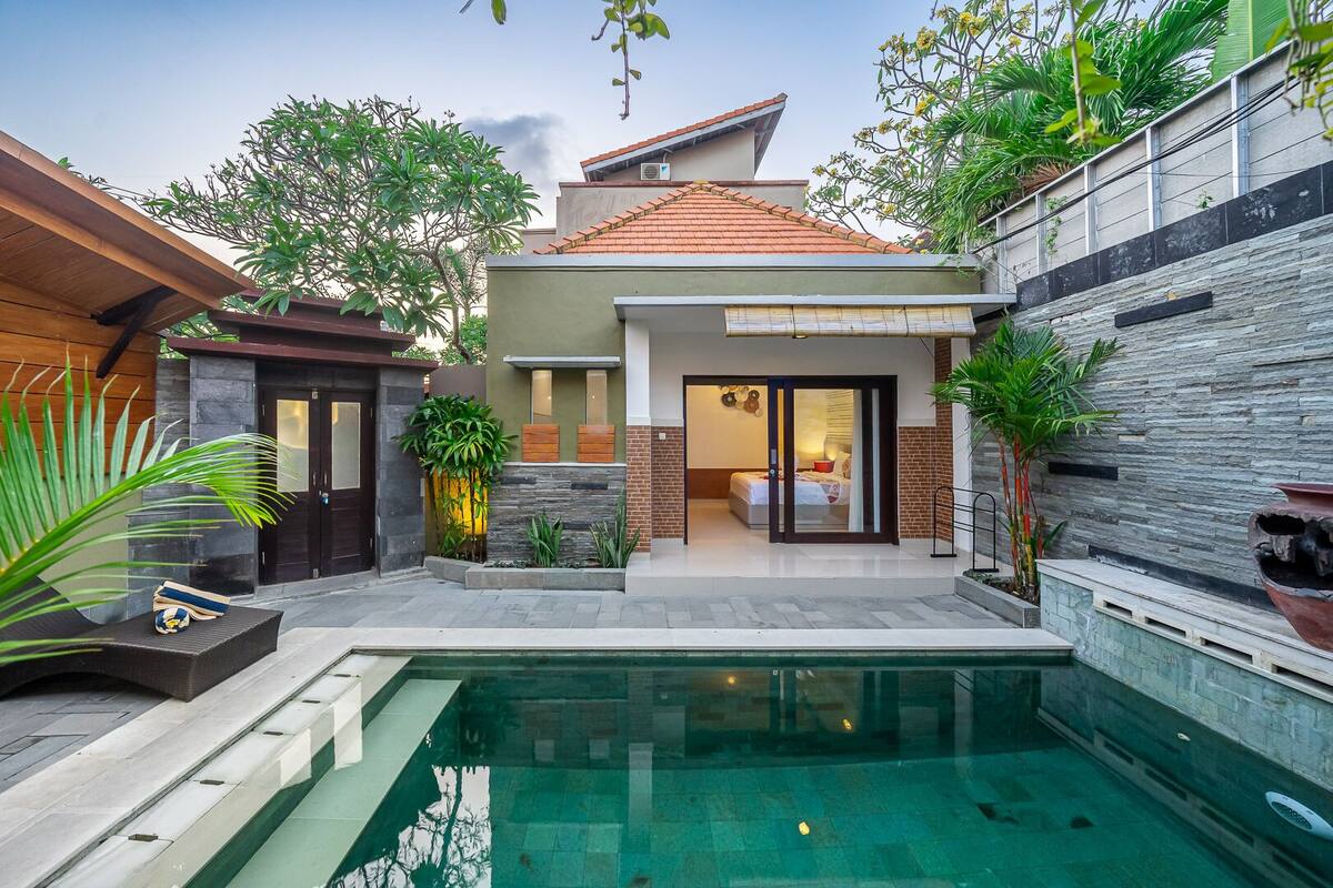 Una casa moderna con piscina, un dormitorio con puerta corredera y una pequeña zona de estar al aire libre.