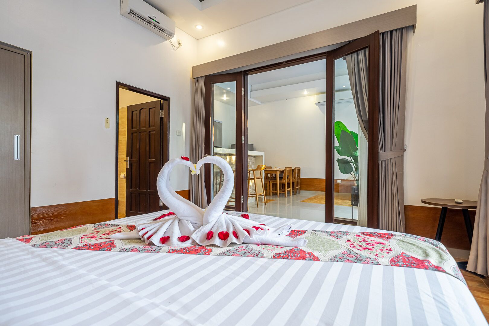 A hotel room with a bed, a dining area, and a sliding glass door.