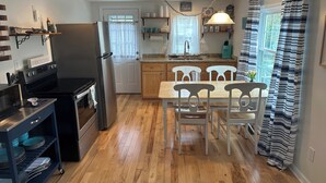 Une cuisine équipée d’une cuisinière, d’un réfrigérateur et d’une table à manger avec des chaises.