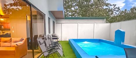 Un'area esterna moderna con erba sintetica, una piccola piscina e zone relax.