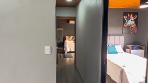 A hallway leading to a bedroom with a bed, a nightstand, and a painting on the wall. - Modern Uvita Beachhouse by Whale's Tale  (Bahía Ballena)