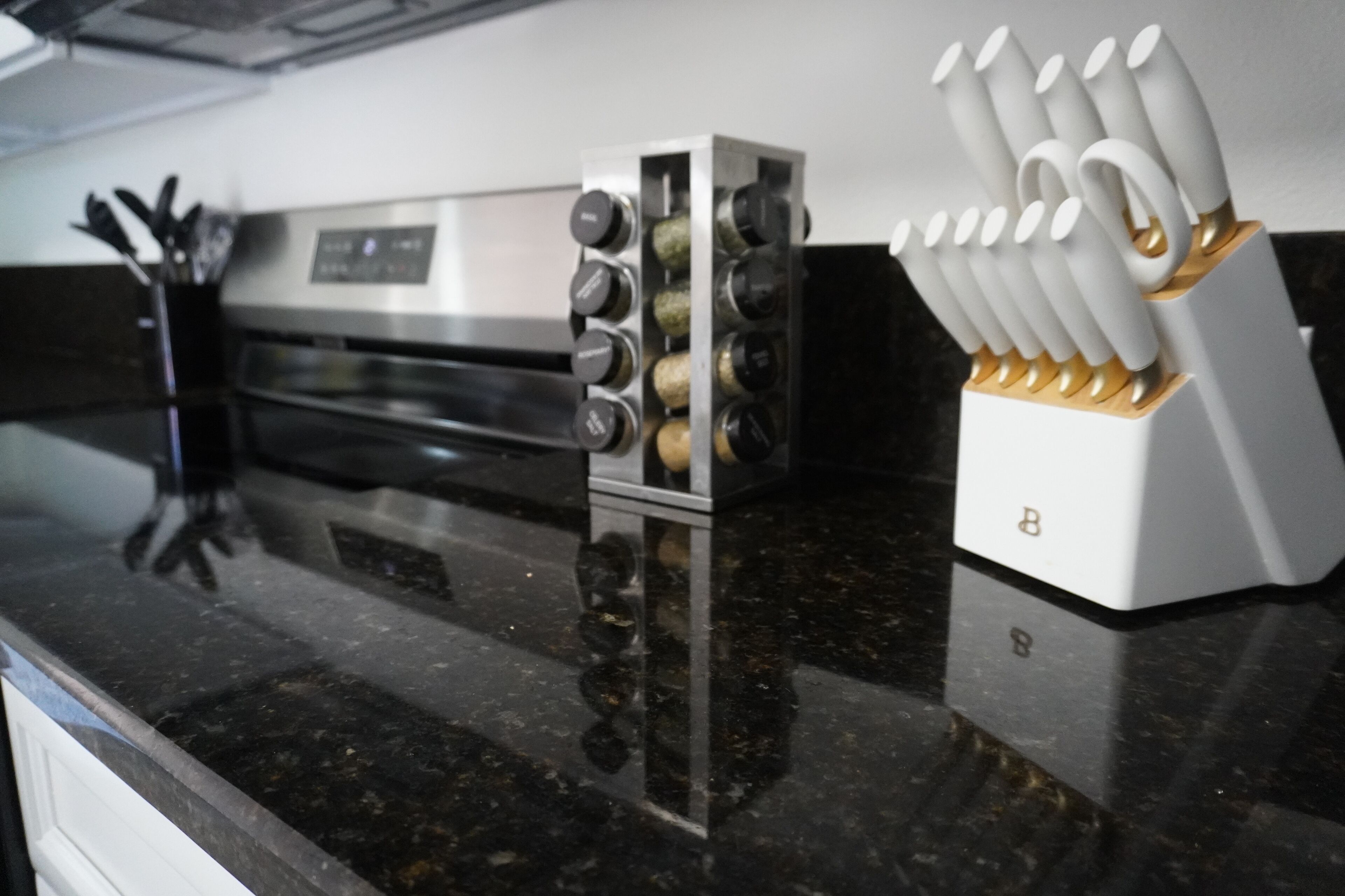 Cocina con horno de acero inoxidable, especiero y bloque de cuchillos sobre encimera de granito.