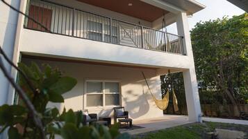 A two-story house with a balcony, outdoor seating, and a hammock.
