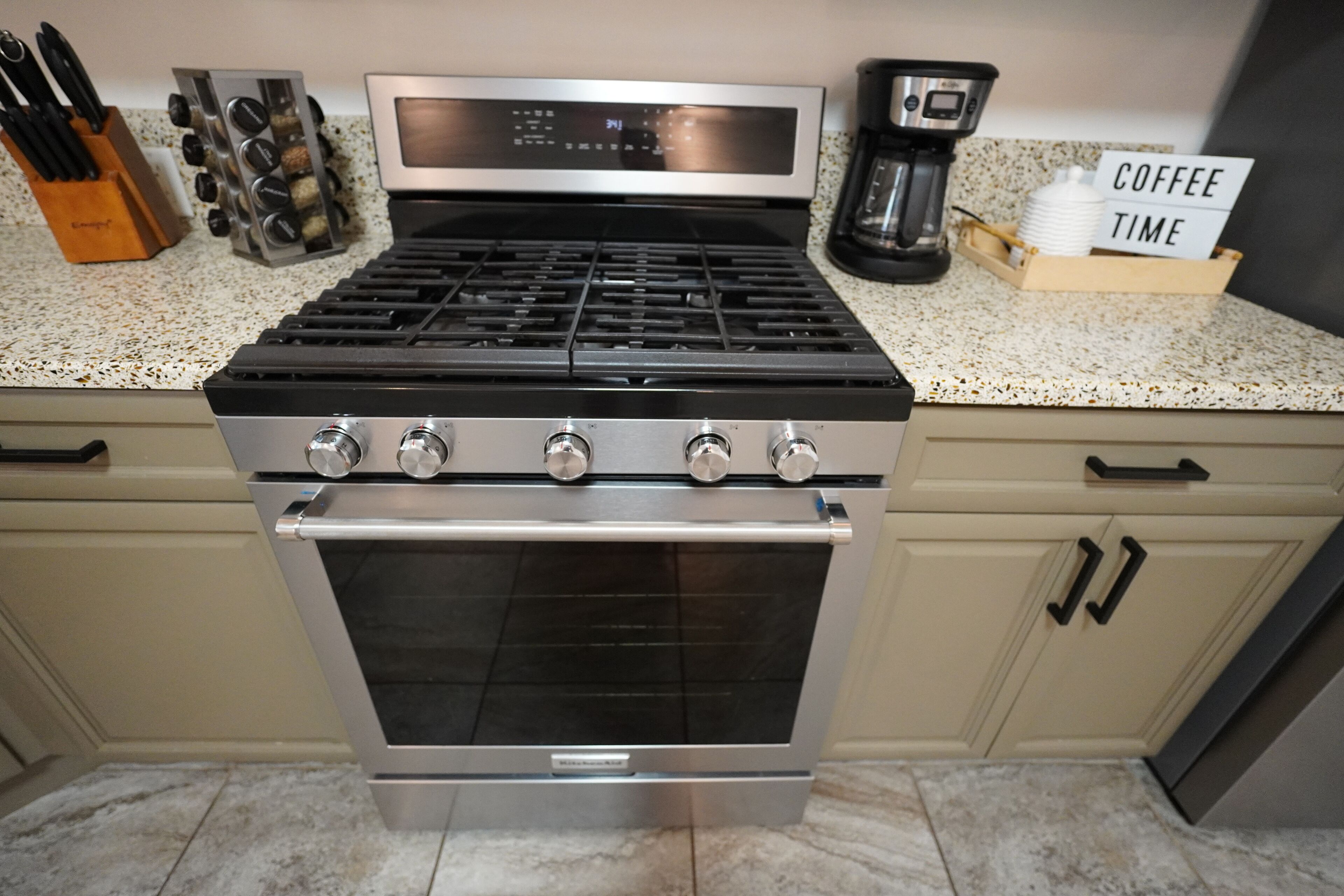 A kitchen with a stainless steel stove, oven, and coffee maker. There is a sign that says "COFFEE TIME".