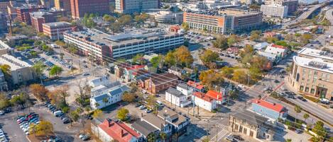 An aerial view of a city with a mix of commercial and residential buildings, a parking lot, and a bridge in the background.