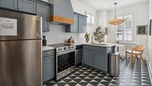 A modern kitchen with grey cabinets, stainless steel appliances, and a patterned floor.