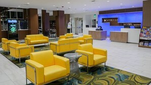 A hotel lobby with yellow seating, a reception desk, and a carpeted floor. - Anaheim | Couples Theme Park Getaway | Pool + Parks (Anaheim)