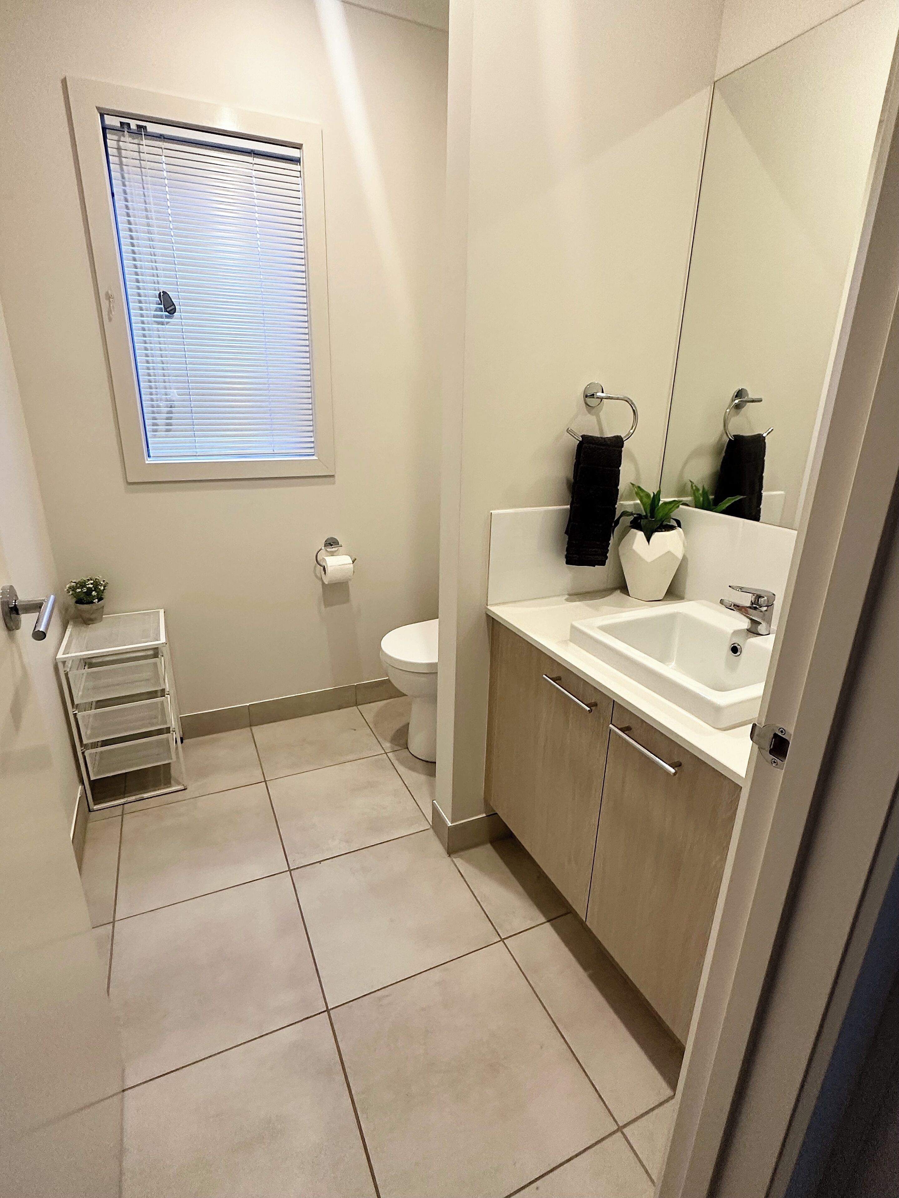 Un baño moderno con inodoro, lavamanos, espejo y ventana.