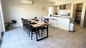 A compact kitchen with a dining area, a clock, and a potted plant. - Spacious Coastal Oasis - 10 min to Torquay, 10 min to Geelong ! (Mount Duneed)