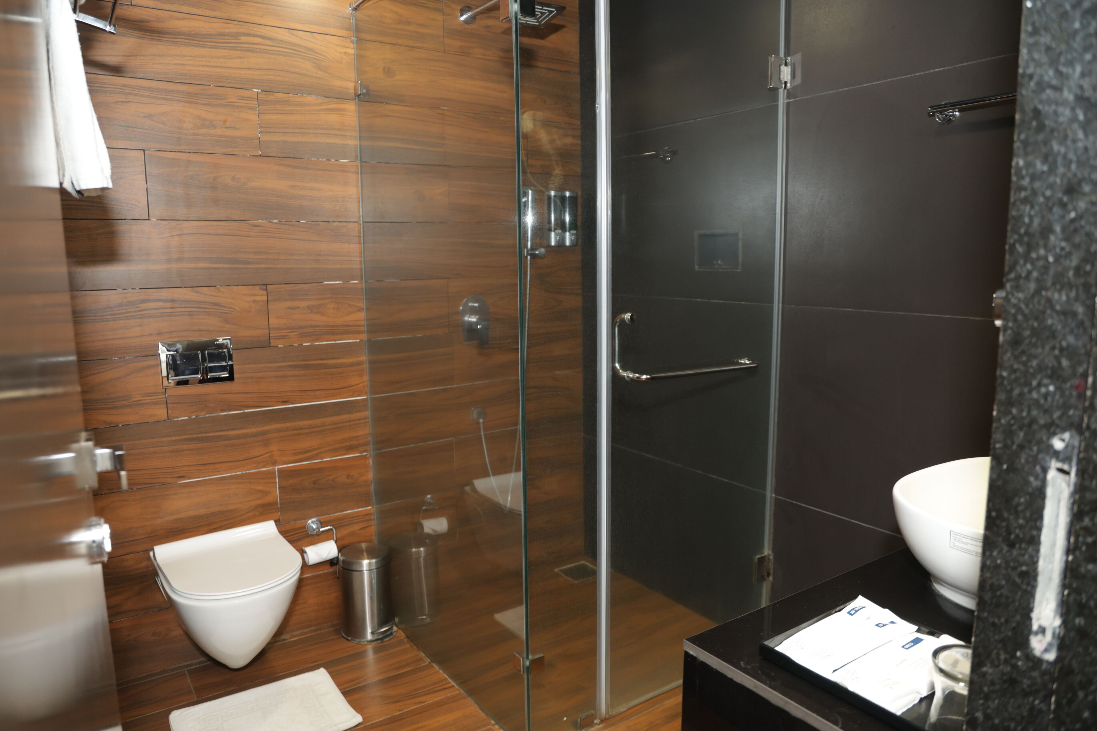 Een moderne badkamer met een douchecabine van glas, een wit toilet en een zwart wastafelmeubel.