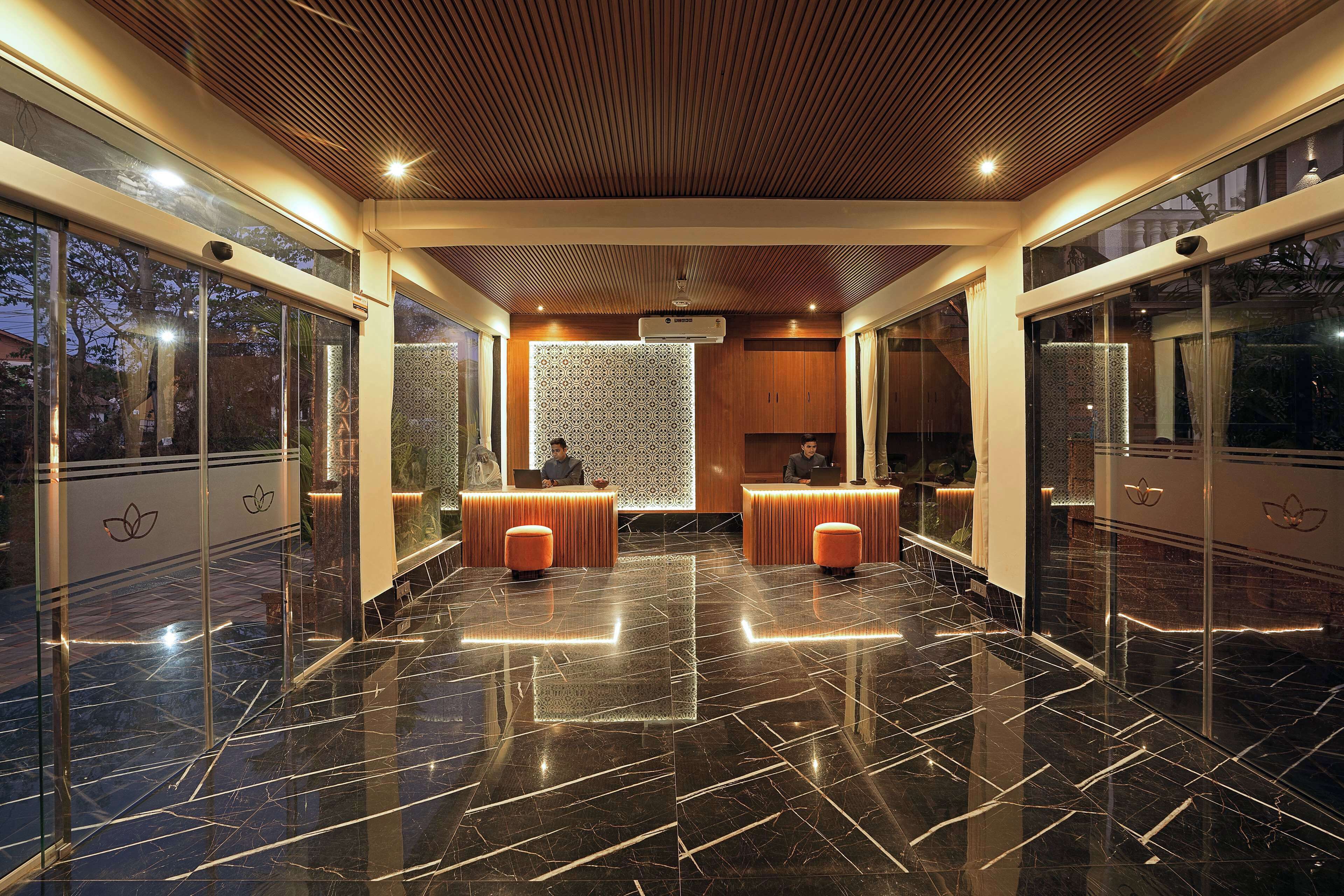 A modern lobby with a polished marble floor, wooden ceiling, and glass walls offering views of the outdoors.