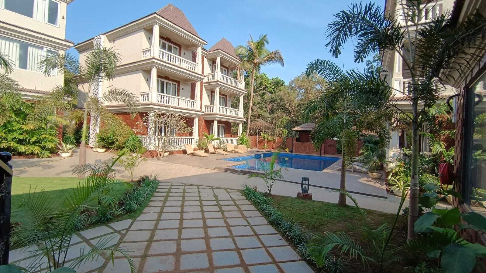 A hotel courtyard with a swimming pool, palm trees, and a paved walkway.